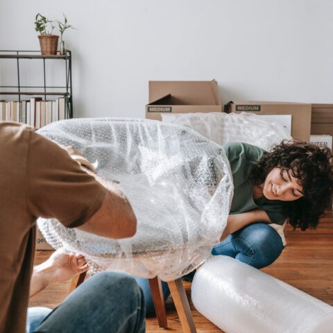 couple wrapping a chair with plastic